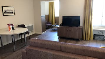 A modern living room with a sofa, TV, and dining area.