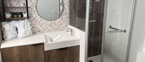 A modern bathroom with a freestanding sink, a round mirror, and a glass-enclosed shower.