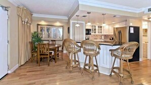 A modern kitchen with a central island, bar stools, and pendant lighting.