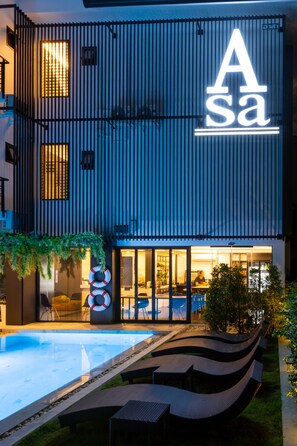 A modern building with a pool, lounge chairs, and a sign that reads "ASA". - Asa Hotel (Chiang Mai)