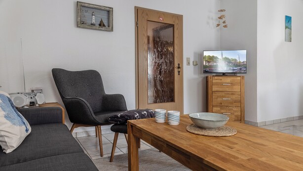 A living room with a sofa, a wooden coffee table, a television, and a cabinet.