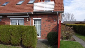 A two-story house with a red-tiled roof, a small balcony, and a number '14' on the front wall.