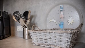 Un comptoir de cuisine sur lequel se trouve un panier tressé contenant des ustensiles de cuisine, un récipient en métal et une assiette décorative ornée de motifs découpés à la main.