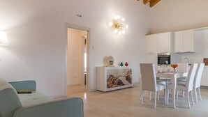 Een moderne keuken met witte kasten, een eettafel met stoelen en een decoratieve lamp.