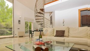 Una sala moderna con una mesa de centro de vidrio, un sofá y una escalera en espiral.