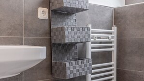 A bathroom with a white sink, a towel rack, and a textured wall shelf.