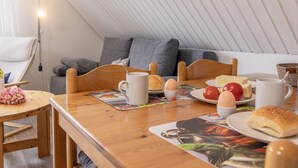 A breakfast setup in a cozy room with a wooden table, a sofa, and a lamp.