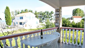 A balcony with a table and chairs, a bottle of wine, and a view of surrounding buildings. - On the first floor with balcony and sea view (Nin)