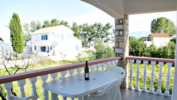 A balcony with a table and chairs, a bottle of wine, and a view of surrounding buildings. - On the first floor with balcony and sea view (Nin)