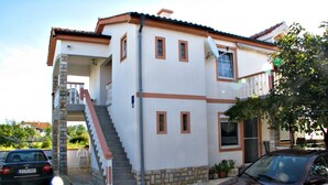 A two-story house with a staircase, a satellite dish, and a car parked in front. - On the first floor with balcony and sea view (Nin)