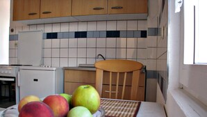 A kitchen with a bowl of fruit on the counter, wooden cabinets, and a tiled backsplash. - On the first floor with balcony and sea view (Nin)