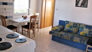 A compact living space with a kitchenette, a dining area, and a sofa. - On the first floor with balcony and sea view (Nin)