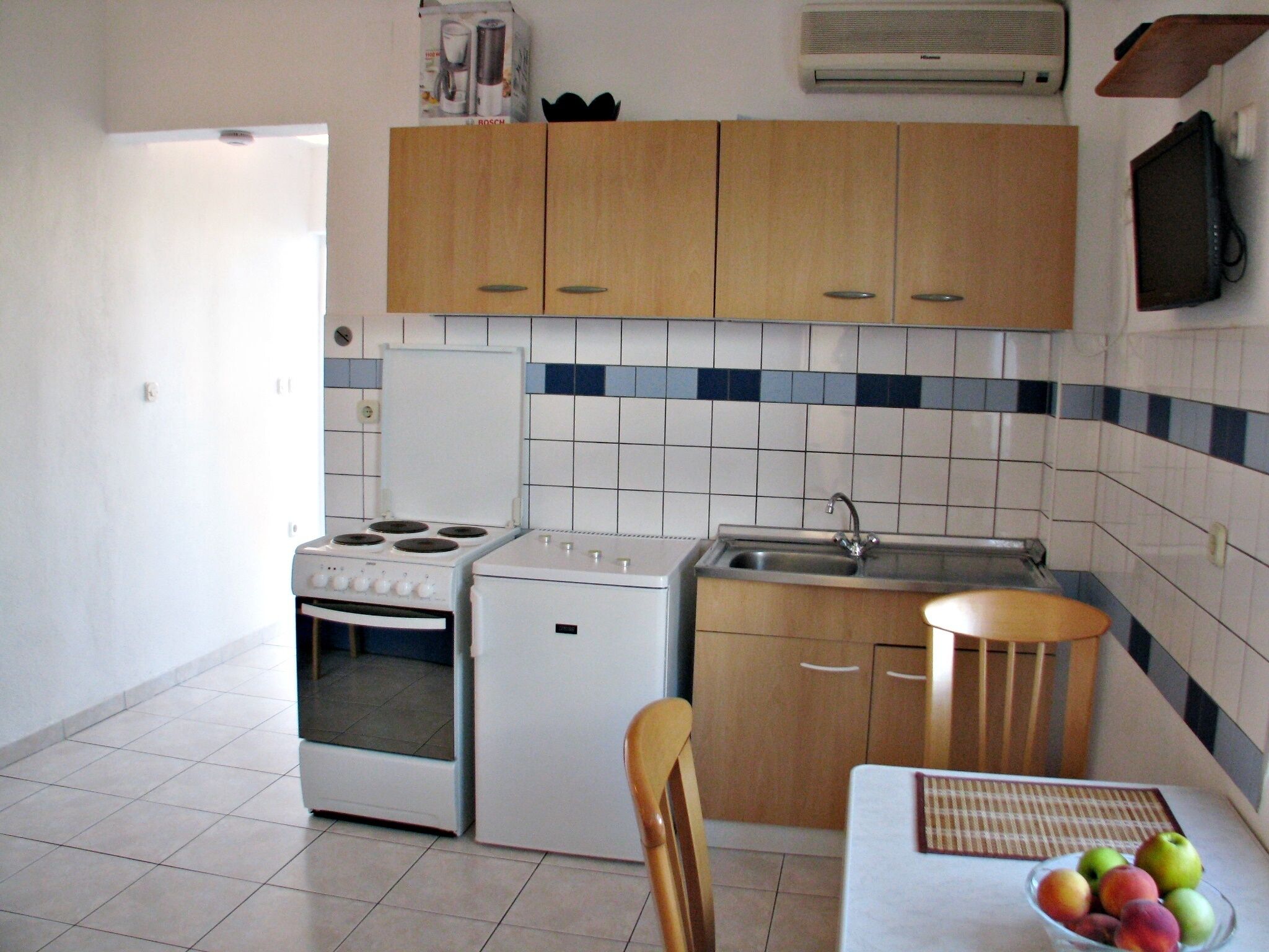 A compact kitchen with a stove, oven, sink, and wooden cabinets.