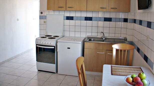 A compact kitchen with a stove, oven, sink, and wooden cabinets. - On the first floor with balcony and sea view (Nin)