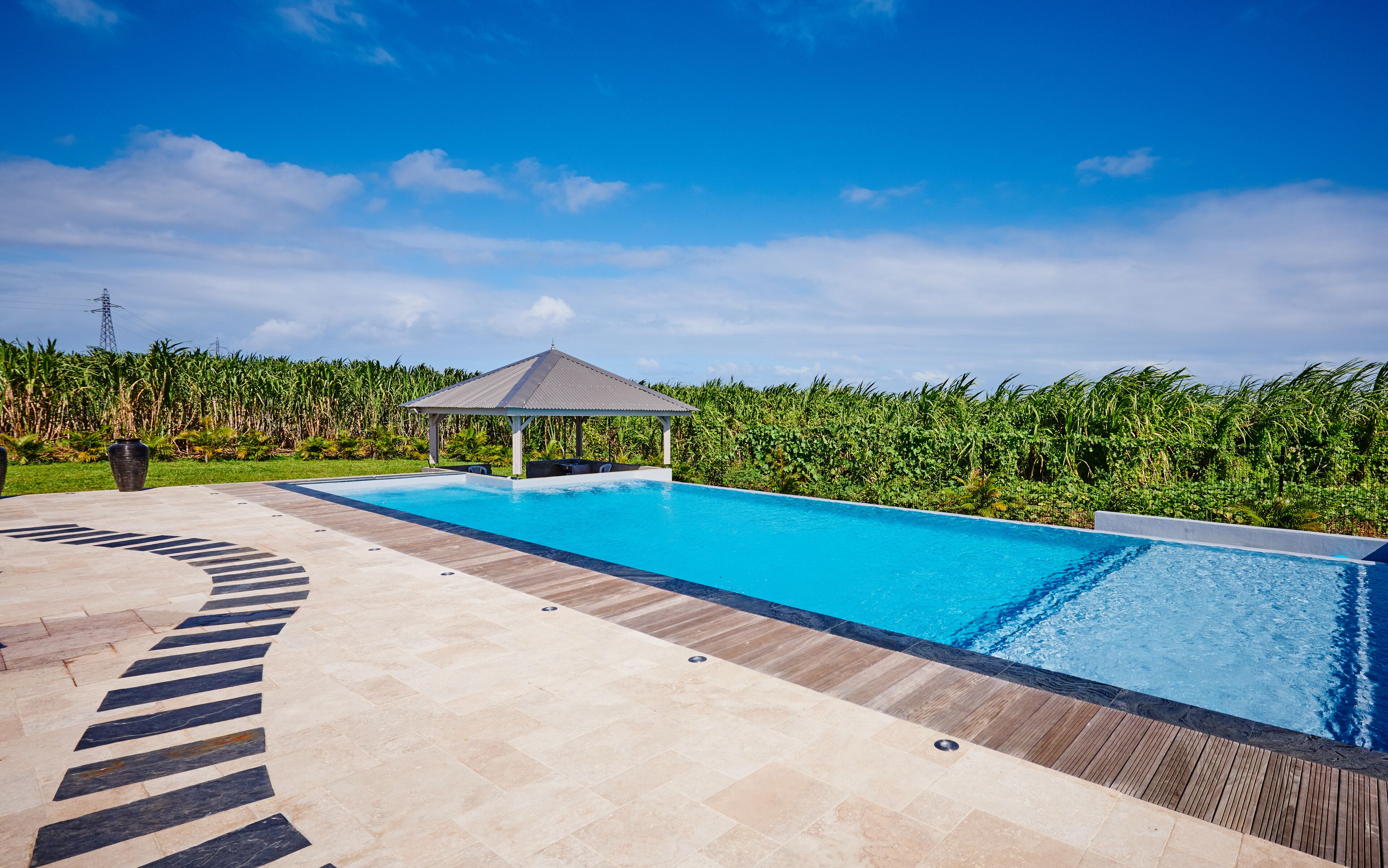 A swimming pool with a wooden deck and a gazebo.