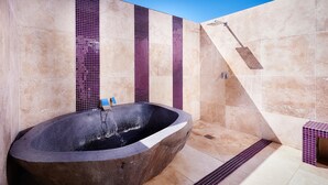 Une salle de bain moderne avec une baignoire sur pieds, des murs carrelés et un espace douche.