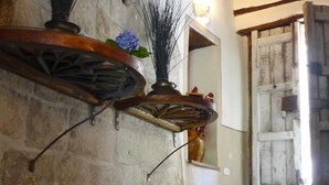 A rustic interior with a stone wall, wooden beams, and a mirror reflecting a door.