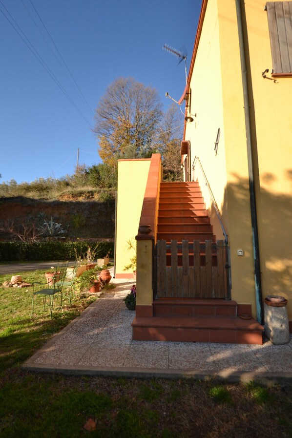A yellow building with a wooden staircase leading to a door.