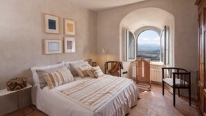 A bedroom with a large bed, a chair, a desk, and a window with a view. - Medioevo&Design, Historical Umbria Tower With Private Pool, gardens, parkings (Todi)