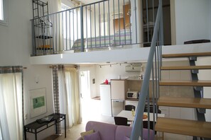 Experience the comfort of a loft bedroom with a view, connected to a spacious living area and kitchen below.