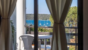 A balcony with a table and chairs, overlooking a body of water with sailboats. - Attractive apartment near beach with BBQ (Banjole)