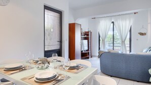 A modern living room with a dining area, a sofa, and a TV stand. - Attractive apartment near beach with BBQ (Banjole)