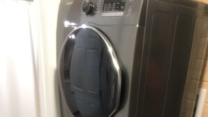 A compact, modern laundry room with a stacked washer and dryer, a small sink, and a toilet. - Eagle Lake Fishing - Getaway Cabin (Waldhof)