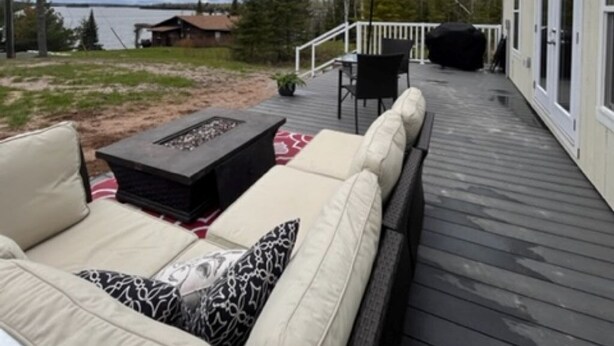 A deck with outdoor furniture, a red umbrella, and a view of a lake. - Eagle Lake Fishing - Getaway Cabin (Waldhof)