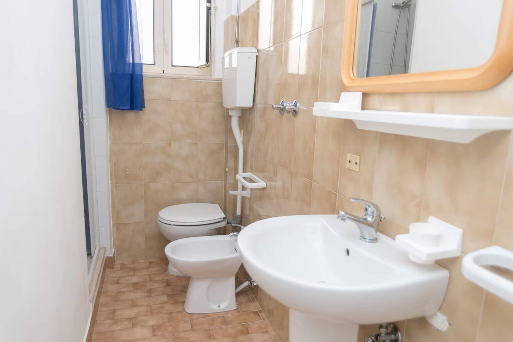 Une petite salle de bain avec deux toilettes, un lavabo, un miroir et une douche.