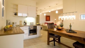 Una cocina moderna con armarios blancos, encimera de madera y un comedor con mesa y sillas de madera.