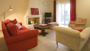 Una sala de estar con chimenea, televisor y sillones a rayas.