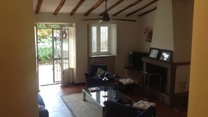 A living room with a fireplace, a television, and a dining area with a table and chairs. - Casanatura Capo Mulini, traditional Sicilian rustic surrounded by nature (Acireale CT)