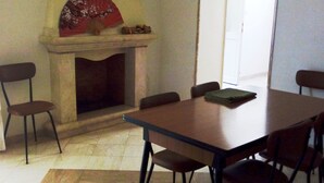 A dining area with a table, chairs, a fireplace, and a fan.