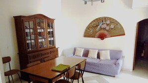 A dining area with a wooden table and chairs, a cabinet with glass doors, and a purple sofa.