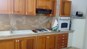 A kitchen with wooden cabinets, a gas stove, a sink, and an oven.