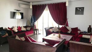 A living room with a sofa set, a coffee table, and a TV. - Beautiful apartment in La Perla 2 4332 (Saidia)