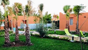 Un jardin agrémenté de palmiers, une piscine et un espace salon extérieur.