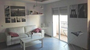 Een moderne woonkamer met een witte bank, een salontafel en een stadsgezicht op de muur.