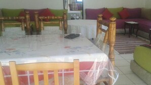 Comedor con una mesa preparada para dos personas, rodeada de sillas de madera con asientos acolchados.