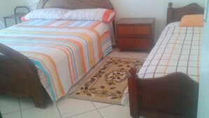 Un dormitorio con cama, mesita de noche, cómoda y una silla.