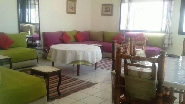 Una sala de estar con un sofá verde, una mesa redonda y una silla de madera.