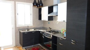 Une cuisine moderne avec des meubles de couleur sombre, une cuisinière à gaz et un évier.