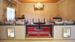 Ein Zimmer mit einer Sofagarnitur, einer Chandelier und dekorativen Wandverkleidungen.