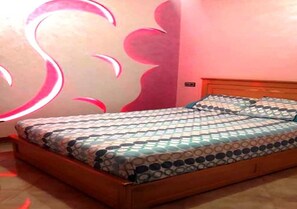 Une chambre avec un lit en bois, une literie à motifs et un mur orné d’appliques lumineuses rondes.