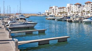 A marina with boats docked, a wooden pier, and buildings with red roofs in the background. - Nice apartment in Réidence Attadamon 4470 (Agadir)