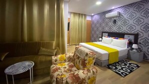 A hotel room with a bed, a sofa, a floral armchair, a small table, and a patterned rug. - Superb villa in Marrakech 4435 (Marrakech)
