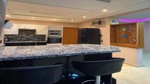 A modern kitchen with granite countertops, a built-in oven, and a microwave. There are two black bar stools in front of the counter. - Superb villa in Marrakech 4435 (Marrakech)
