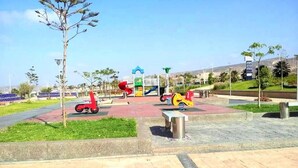 Une aire de jeux avec un toboggan rouge et jaune, une structure d’escalade bleue et jaune, et un mur d’escalade vert et jaune.