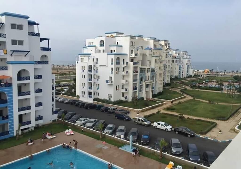 Un immeuble résidentiel doté de nombreux balcons, d’une piscine et d’un espace de stationnement.