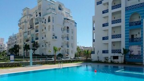 Una piscina rodeada de edificios de varios pisos con balcones.